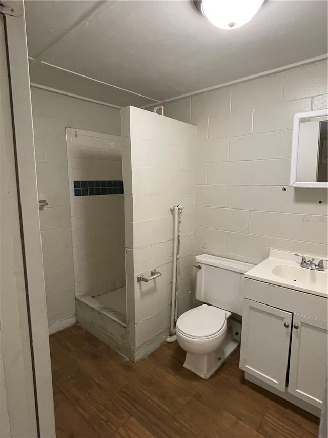 bathroom featuring tiled shower, wood-type flooring, toilet, and vanity