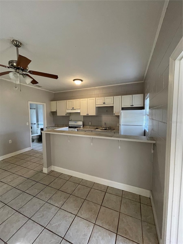 kitchen with a breakfast bar, white cabinets, white appliances, and kitchen peninsula