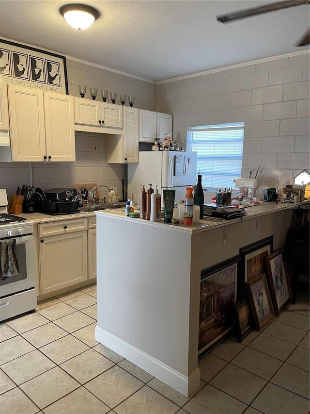 kitchen featuring backsplash, light tile patterned floors, gas range gas stove, and white cabinets