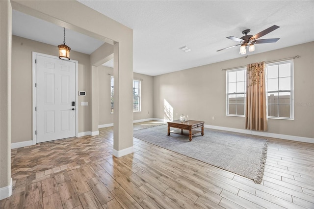 foyer featuring ceiling fan, a textured ceiling, and light wood-type flooring