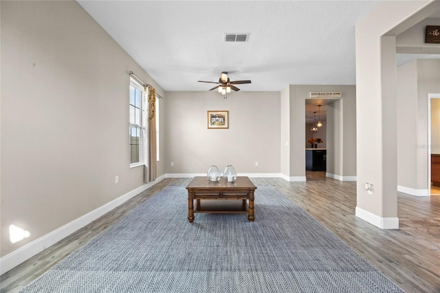 living area with wood-type flooring, a textured ceiling, and ceiling fan