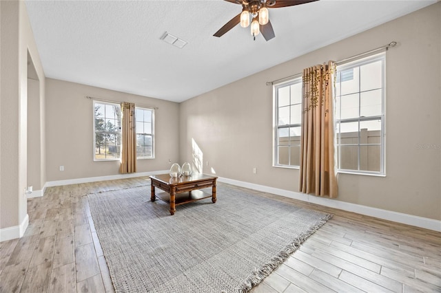 living area with ceiling fan, light hardwood / wood-style flooring, and a textured ceiling