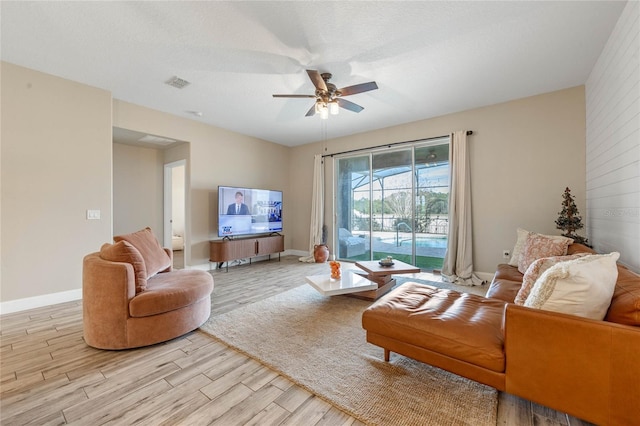 living room featuring ceiling fan, a textured ceiling, and light wood-type flooring