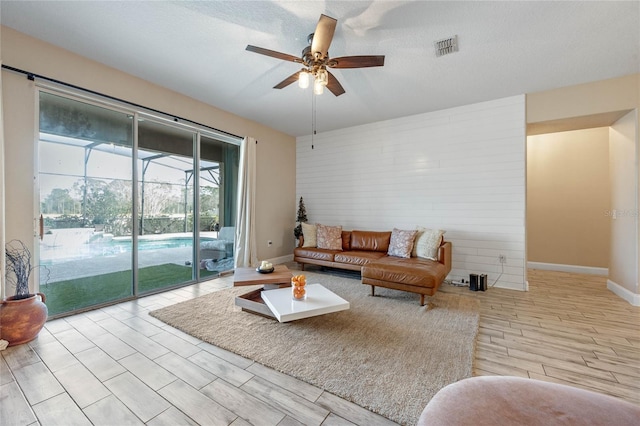 living room featuring light wood-type flooring, a textured ceiling, and ceiling fan