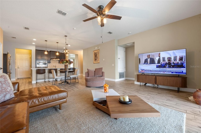 living room with ceiling fan and light hardwood / wood-style flooring