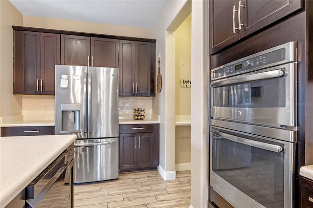 kitchen featuring stainless steel appliances, tasteful backsplash, dark brown cabinets, and light hardwood / wood-style flooring