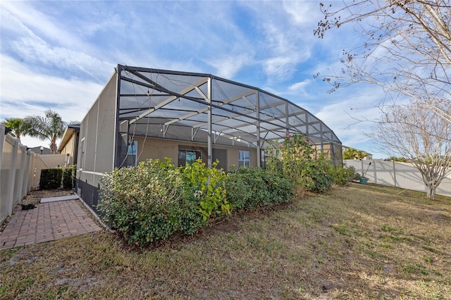 rear view of house with a yard and glass enclosure