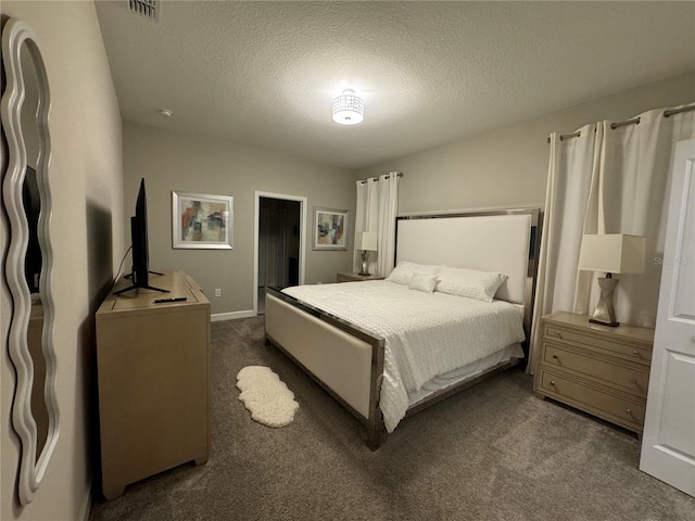 bedroom with a textured ceiling and dark colored carpet