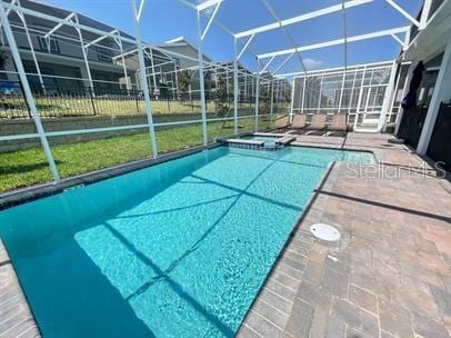 view of pool with a lanai, a patio area, and an in ground hot tub