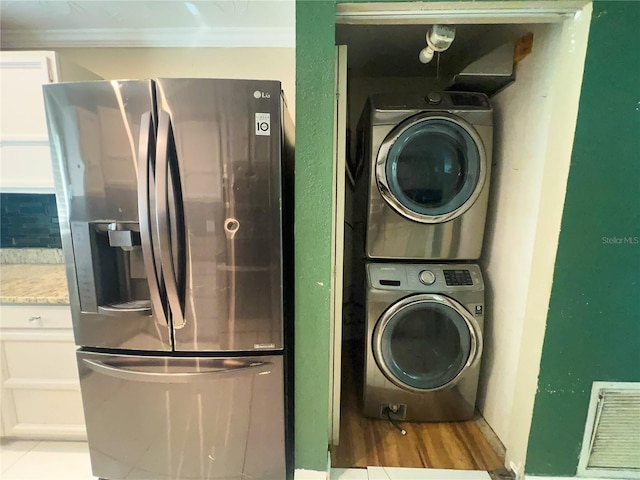 laundry room with stacked washer and dryer, ornamental molding, and light hardwood / wood-style flooring