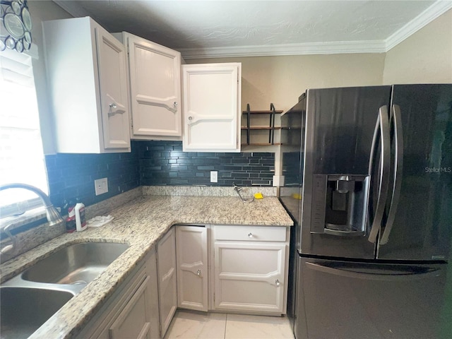 kitchen featuring sink, stainless steel fridge, light stone countertops, ornamental molding, and white cabinets