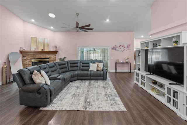 living room featuring ceiling fan, dark hardwood / wood-style flooring, and a brick fireplace