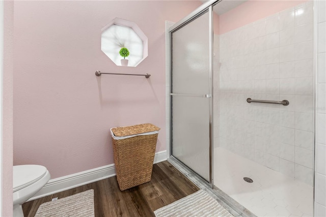 bathroom with hardwood / wood-style flooring, toilet, and a shower with shower door