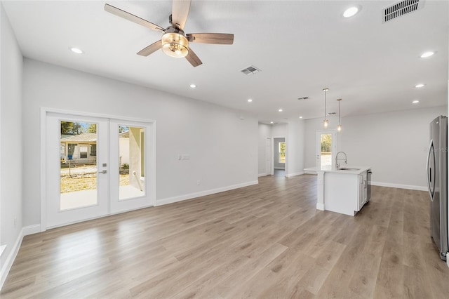 unfurnished living room with sink, light hardwood / wood-style flooring, french doors, and ceiling fan