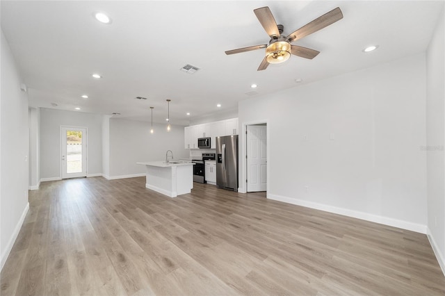 unfurnished living room with ceiling fan, sink, and light hardwood / wood-style flooring