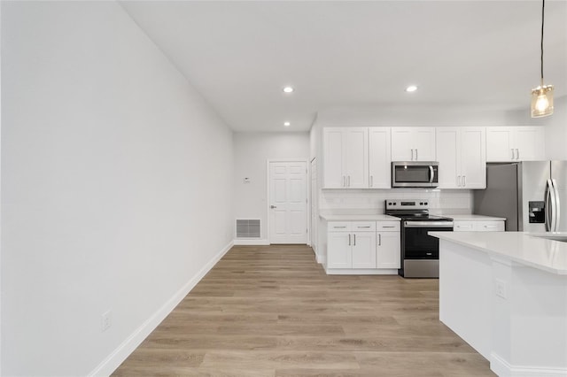 kitchen with decorative light fixtures, white cabinetry, backsplash, stainless steel appliances, and light wood-type flooring