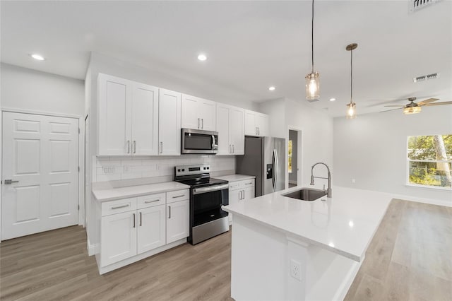 kitchen with pendant lighting, an island with sink, white cabinetry, sink, and stainless steel appliances