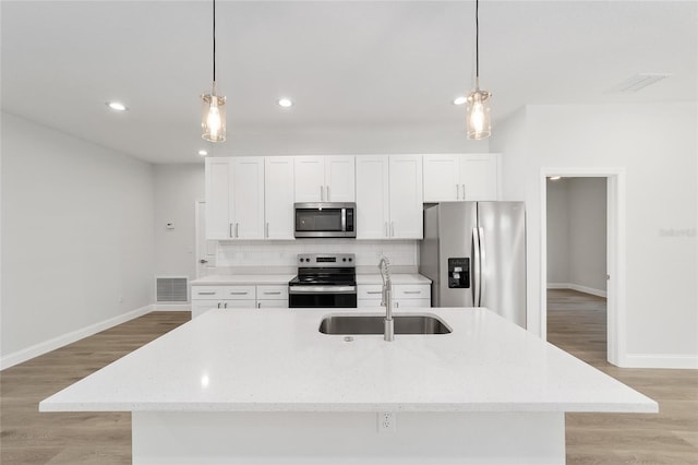 kitchen featuring sink, hanging light fixtures, stainless steel appliances, and an island with sink