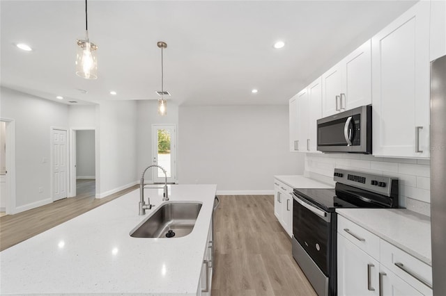 kitchen with decorative light fixtures, tasteful backsplash, sink, white cabinets, and stainless steel appliances