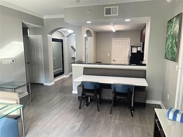 kitchen with ornamental molding, black fridge, and hardwood / wood-style floors