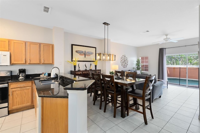 kitchen featuring stainless steel electric stove, sink, dark stone countertops, hanging light fixtures, and a kitchen island with sink