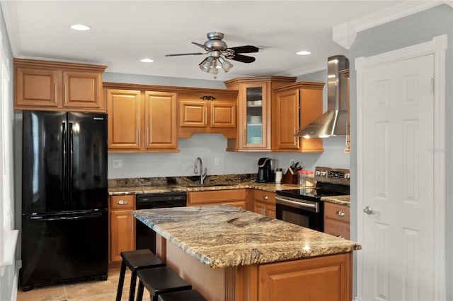 kitchen featuring wall chimney range hood, sink, a breakfast bar area, light stone counters, and black appliances