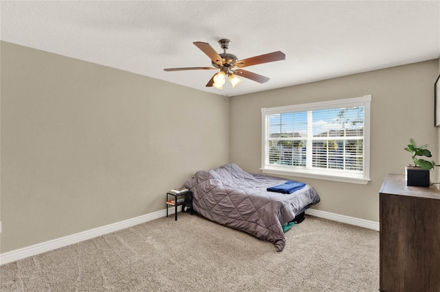 bedroom with ceiling fan, light colored carpet, and a textured ceiling