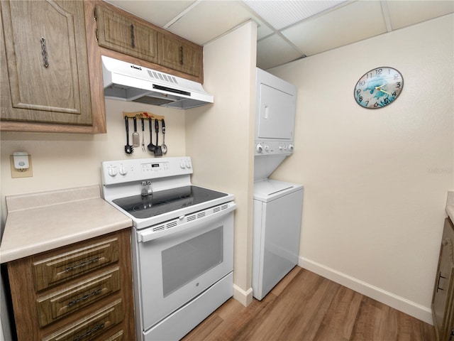 kitchen featuring a paneled ceiling, light hardwood / wood-style floors, stacked washer / dryer, and white range with electric stovetop