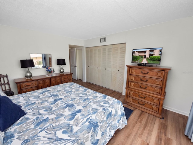 bedroom with a closet, light hardwood / wood-style floors, and a textured ceiling