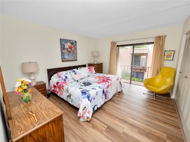 bedroom featuring hardwood / wood-style flooring, access to exterior, a closet, and a textured ceiling