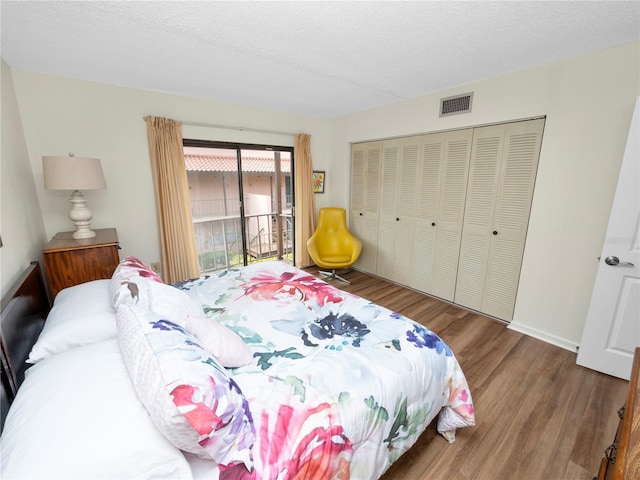 bedroom with access to outside, hardwood / wood-style floors, a textured ceiling, and a closet