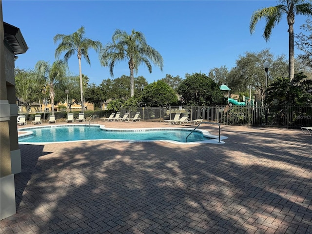 view of swimming pool featuring a patio and a playground