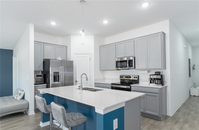 kitchen with a kitchen bar, sink, decorative light fixtures, an island with sink, and stainless steel appliances