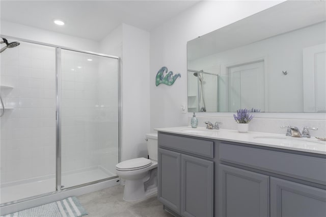 bathroom featuring a shower with door, vanity, and toilet