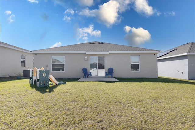 back of property with cooling unit, a playground, and a lawn