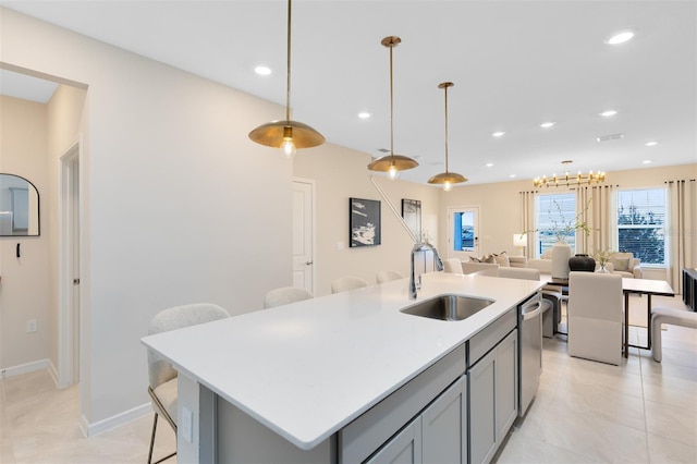 kitchen featuring gray cabinets, pendant lighting, sink, and a center island with sink