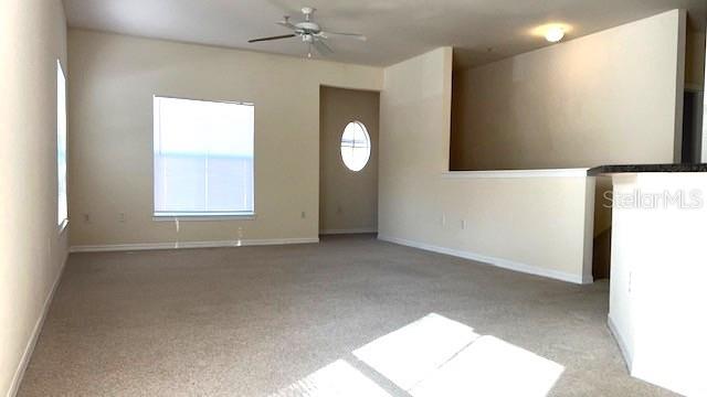 carpeted spare room featuring ceiling fan