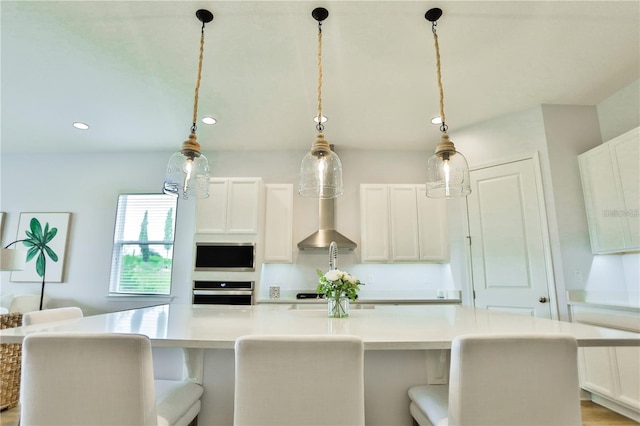 kitchen featuring hanging light fixtures, white cabinetry, a large island, and stainless steel oven