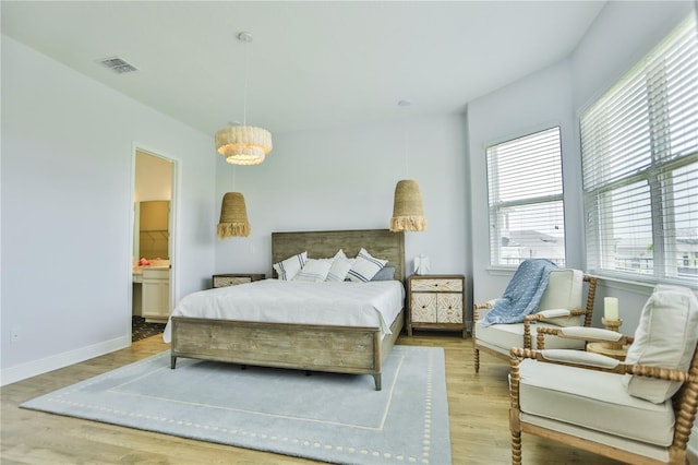 bedroom with connected bathroom and light hardwood / wood-style floors