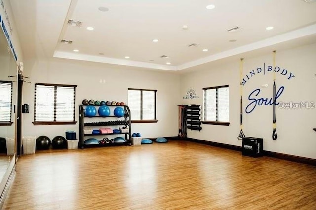 workout room with wood-type flooring and a tray ceiling