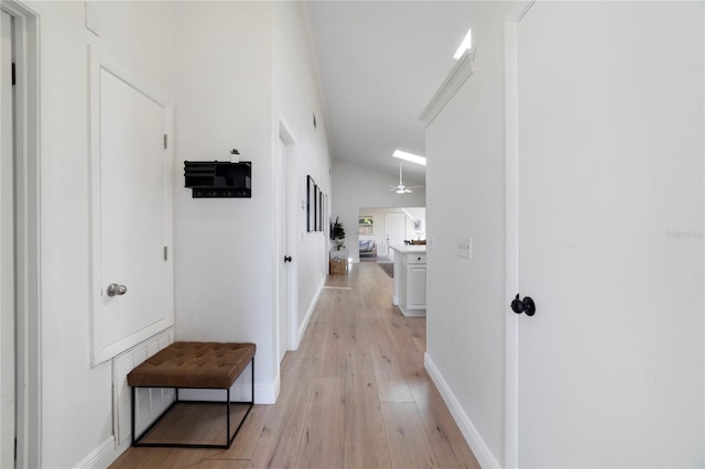 hall with vaulted ceiling and light hardwood / wood-style flooring