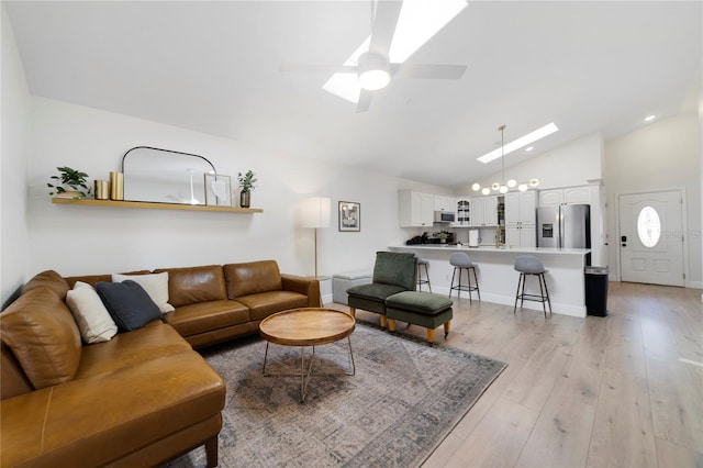 living room with high vaulted ceiling, ceiling fan with notable chandelier, and light wood-type flooring