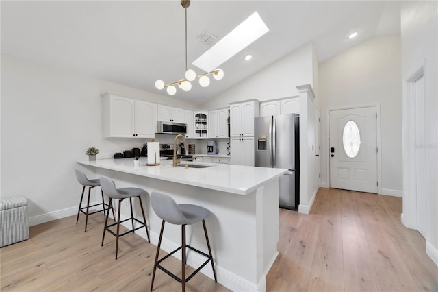 kitchen with white cabinetry, decorative light fixtures, stainless steel appliances, and kitchen peninsula