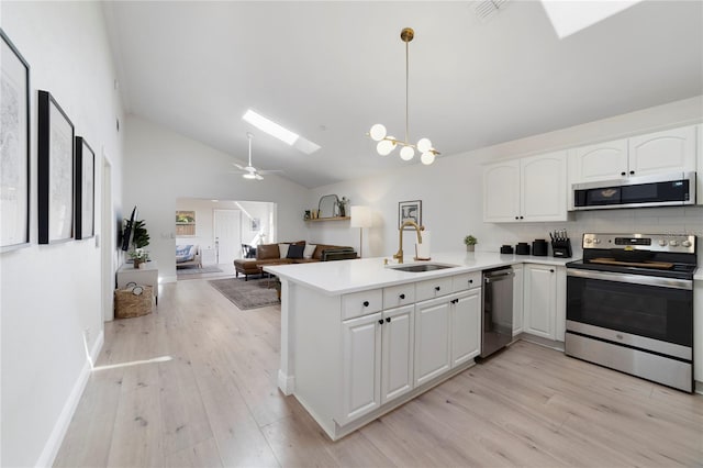 kitchen featuring appliances with stainless steel finishes, a skylight, decorative light fixtures, white cabinetry, and kitchen peninsula