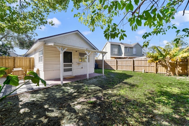 rear view of house featuring a yard and a patio area