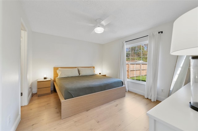 bedroom with ceiling fan, light hardwood / wood-style flooring, and a textured ceiling