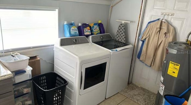 laundry area featuring electric water heater, light tile patterned floors, and washer and dryer