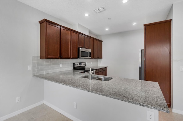 kitchen featuring sink, appliances with stainless steel finishes, backsplash, light stone countertops, and kitchen peninsula