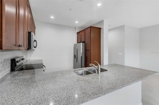 kitchen featuring appliances with stainless steel finishes, sink, light stone counters, and kitchen peninsula