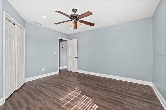 unfurnished bedroom featuring dark wood-type flooring, a closet, and ceiling fan